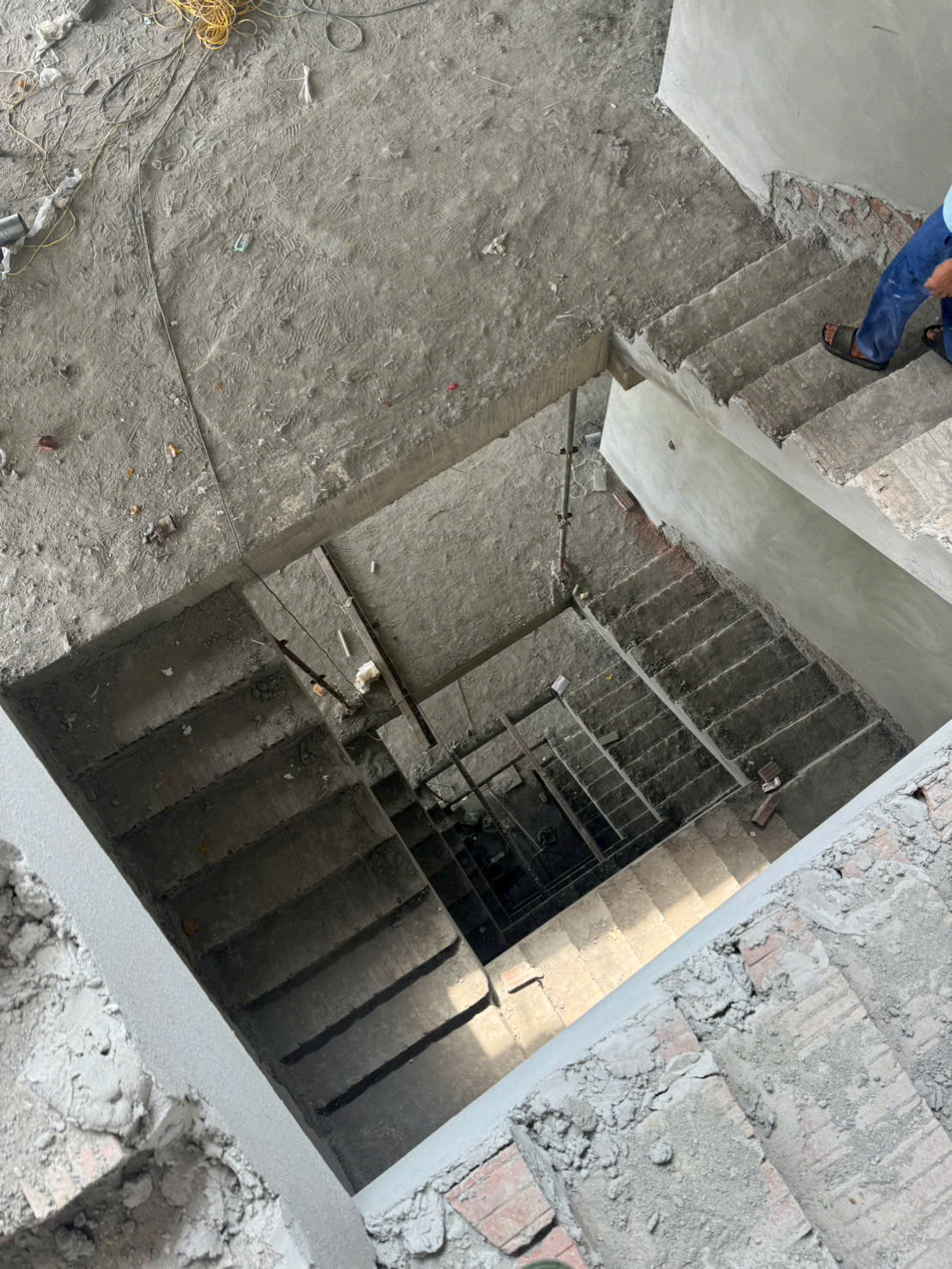 Cầu thang bê tông đang xây dựng trong tòa nhà thô, công nhân đứng trên bậc thang